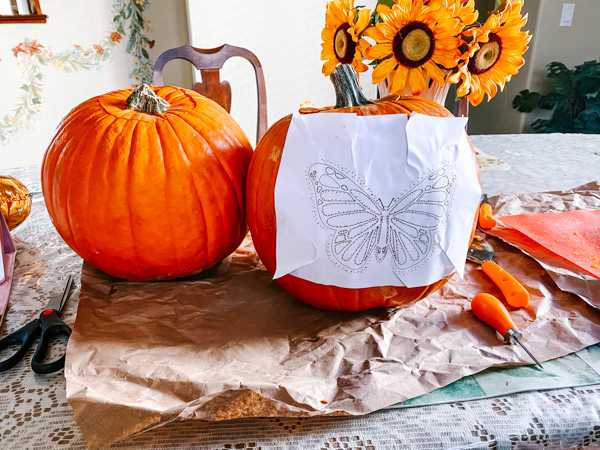 Two pumpkins, one with butterfly design taped on